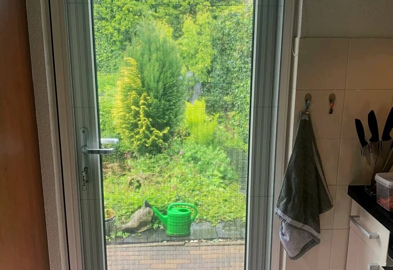 Gesloten plissehordeur met zicht op de tuin