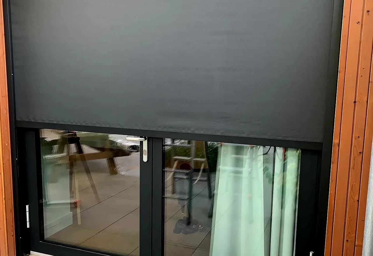 Antraciet screen gedeeltelijk neergelaten voor een glazen pui